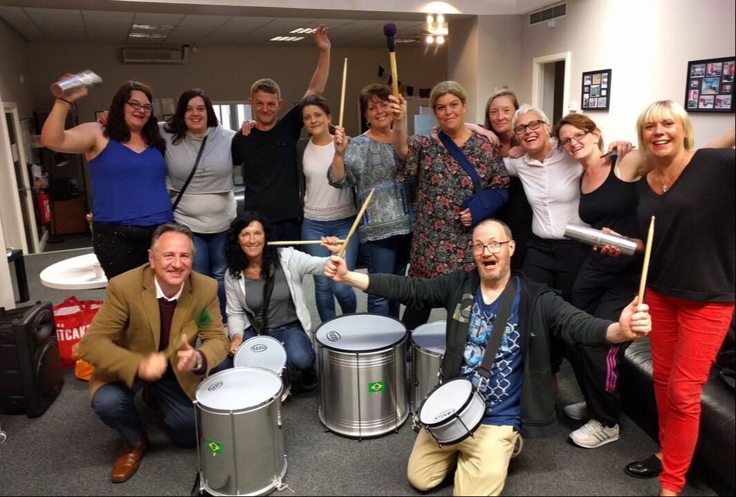 Adults drum party, posing with their instruments